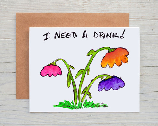 front side of hand-drawn, hand-painted card of a colorful, whimsical watercolor drooping flowers, with the words "I Need A Drink!" across the top, with brown kraft envelope behind it on a background of white-washed wood